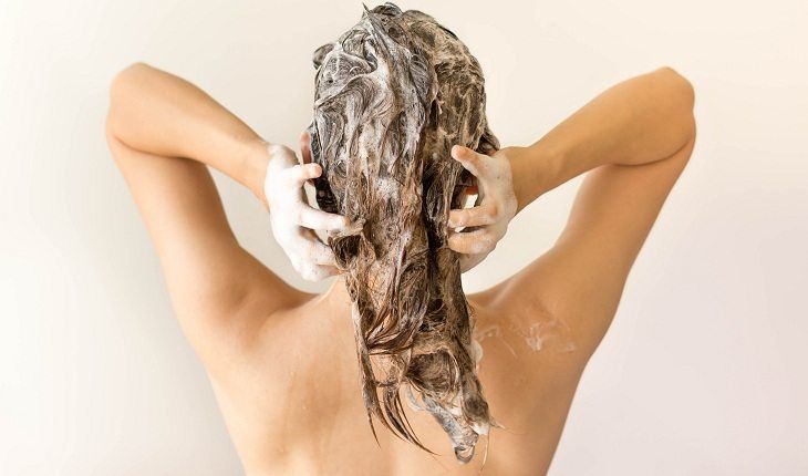 mulher lavando o cabelo com shampoo